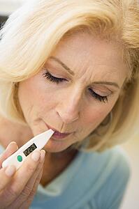 Woman Taking Her Temperature With Thermometer