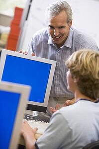 Teacher with male student in computer class