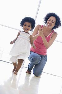 Mother and daughter indoors playing and smiling