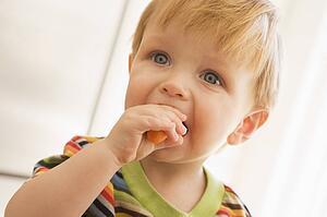 Young boy eating carrot indoors
