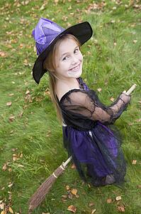 Young girl outdoors in witch costume on Halloween