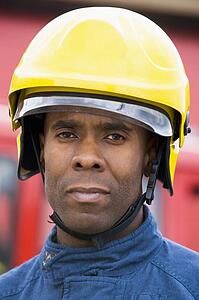 Fireman standing by fire engine wearing helmet