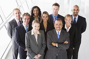 Group of co-workers standing in office space smiling (high key)
