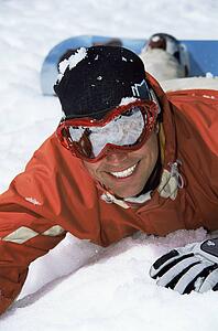 Snowboarder lying on hill smiling (selective focus)