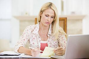 Woman in dining room with laptop smiling