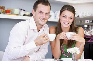 Young couple sitting at a table and having tea together