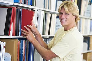 Man in library pulling book off a shelf (depth of field)