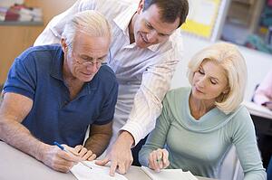 Adult students in class with teacher helping