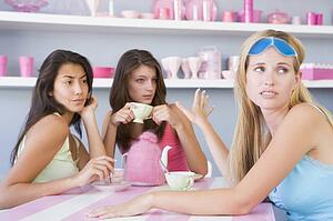 Young woman with a hangover sitting at a table with two friends
