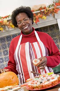 Woman in kitchen making Halloween treats and smiling