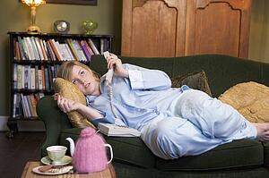 Young woman lying on sofa at home holding telephone