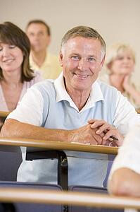 Man sitting in adult classroom with students in background (selective focus)
