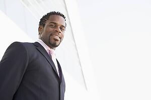 Businessman standing outdoors by building smiling