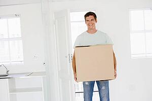 Man with box moving into new home smiling