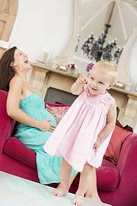 Pregnant mother holding belly in pain with daughter pointing in foreground