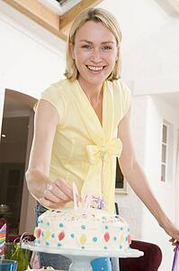 Woman putting candles in cake smiling