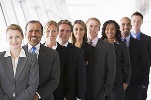 Group of co-workers standing in office space smiling (high key/depth of field)