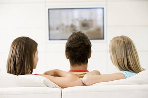 Three friends in living room watching television