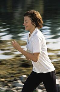 Woman outdoors by a stream running and smiling (selective focus)