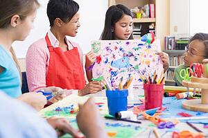Student showing teacher and classmates her artwork (selective focus)