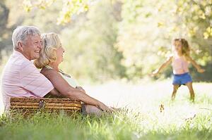 Grandparents at a picnic with young girl in background dancing