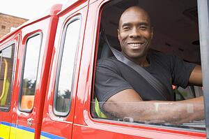 Fireman sitting in fire engine looking out window