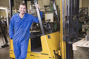 Warehouse worker standing by forklift
