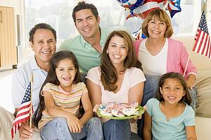 Family in living room on fourth of July with flags and cookies smiling