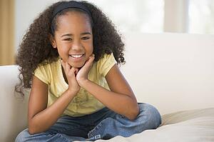 Young Girl Sitting Cross Legged On A Sofa At Home