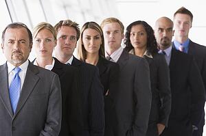 Group of co-workers standing in office space smiling (high key/depth of field)