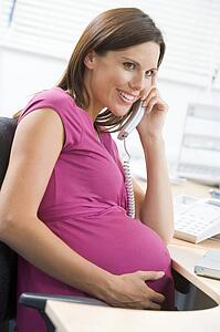 Pregnant woman at work using telephone smiling