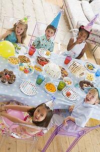 Young children at party sitting at table with food smiling