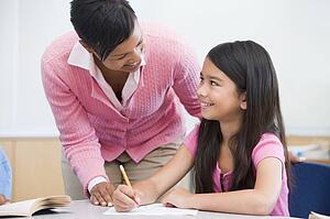 Student in class writing with teacher