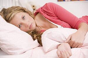 Teenage Girl Lying On Her Bed Looking Sick 