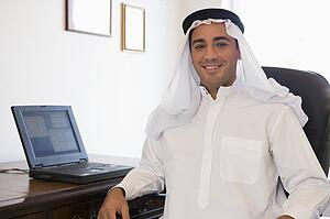 Man in office with laptop smiling (high key/selective focus)