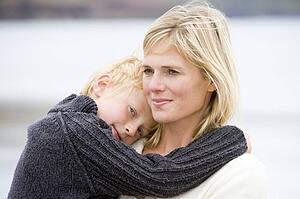 Mother holding son at beach smiling