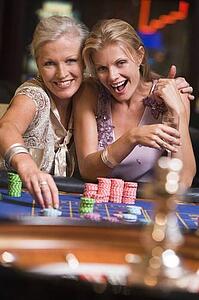 Two women in casino playing roulette and smiling (selective focus)