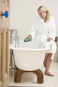 Woman in bathroom putting bubble bath in bathtub