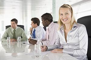 Four businesspeople in a boardroom smiling