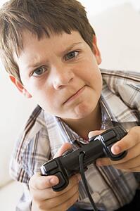Young boy holding video game controller looking confused