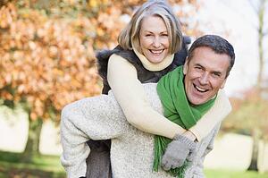 Senior man outdoors piggybacking woman and smiling (selective focus) 