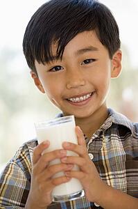 Young boy indoors drinking milk smiling