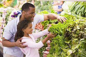 Father and daughter shopping for lettuce at a grocery store