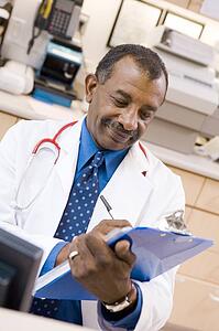 A Doctor Writing On A Clipboard At The Reception Area Of A Hospital