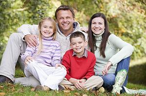 Family sitting outdoors smiling (selective focus)