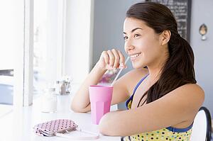 Young woman sitting by a window and having a cold drink