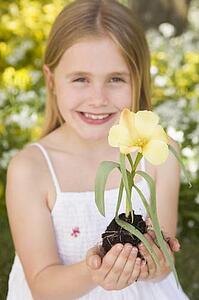 Young girl outdoors holding flower smiling