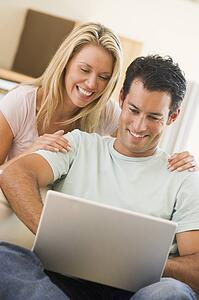 Couple in living room using laptop smiling