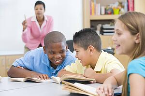 Students in class talking with teacher in background (selective focus)