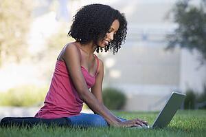 Woman outdoors sitting on grass with laptop (selective focus)